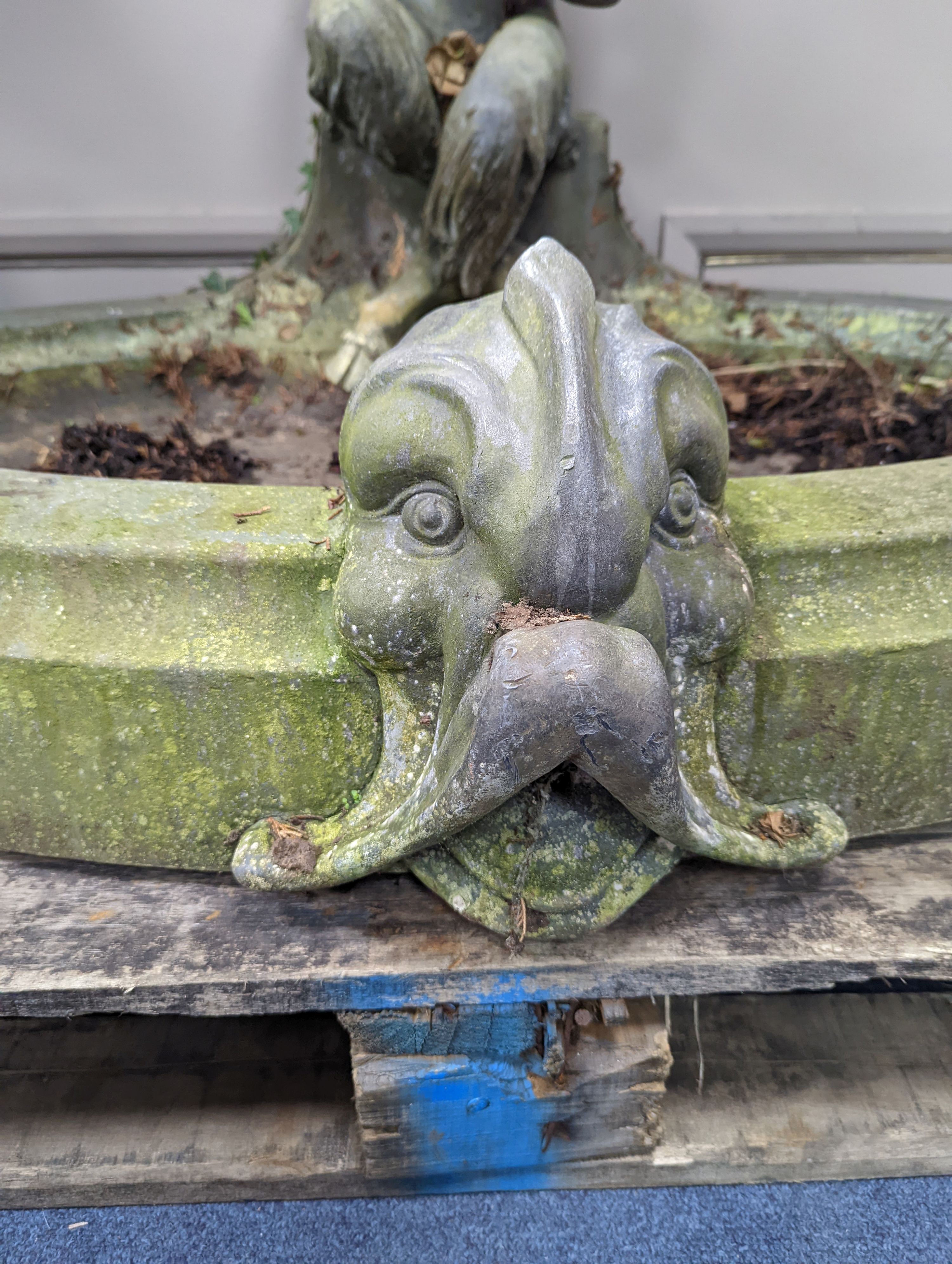 An early 20th century oval lead garden fountain formed as a seated satyr playing pan pipes with stylised dolphin spout, width 120cm, depth 84cm, height 74cm